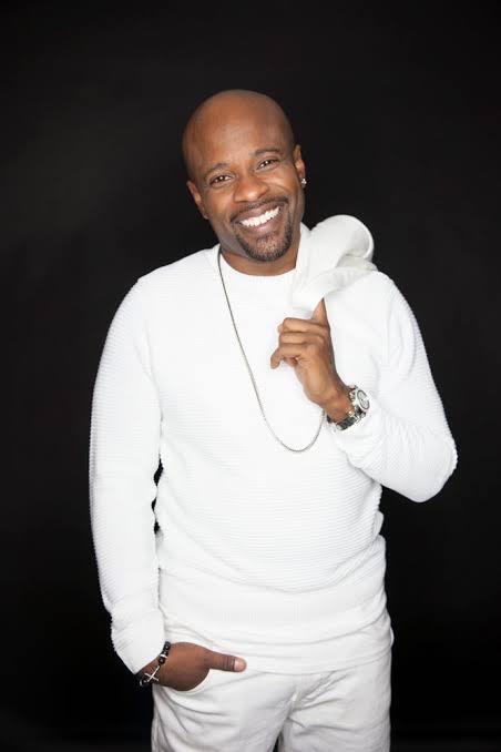 Case smiling in a white sweater and trousers